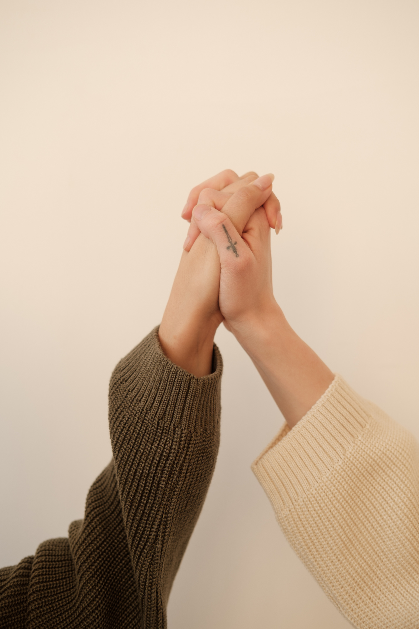 Two Female Hands in Sweater Sleeves Clasped Together